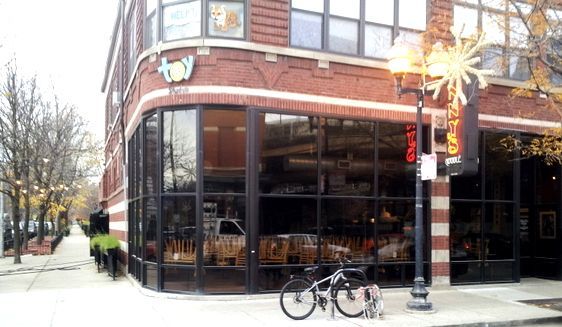 A bicycle is parked in front of a building that says joy