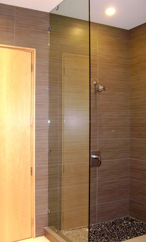 A bathroom with a walk in shower and a wooden door.