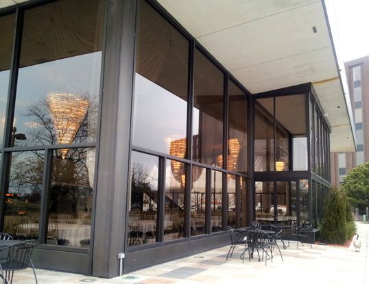 A large building with lots of windows and tables and chairs outside