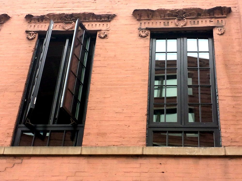 Two windows are open on a brick building