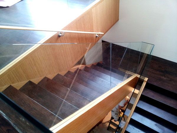 A wooden staircase with a clear glass railing