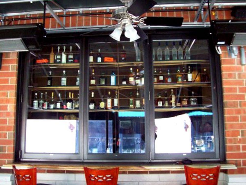 A bar with a ceiling fan and lots of bottles on shelves