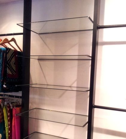 A glass shelf with clothes hanging on it in a store