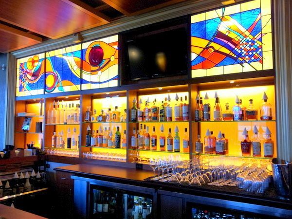 A bar with a lot of bottles and glasses on shelves