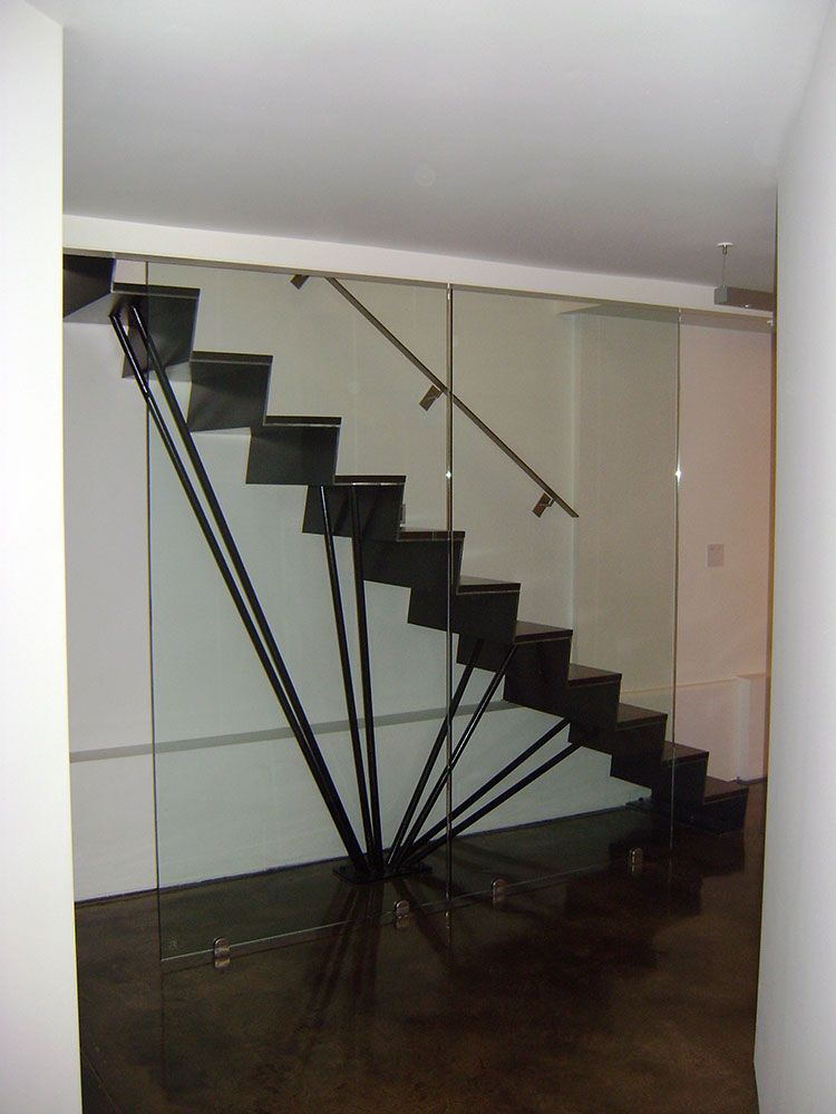 A black staircase with a glass railing in a hallway
