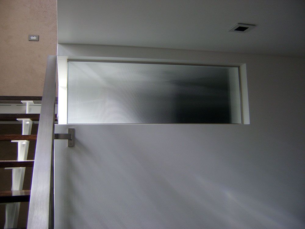 A white wall with a window and stairs in the background