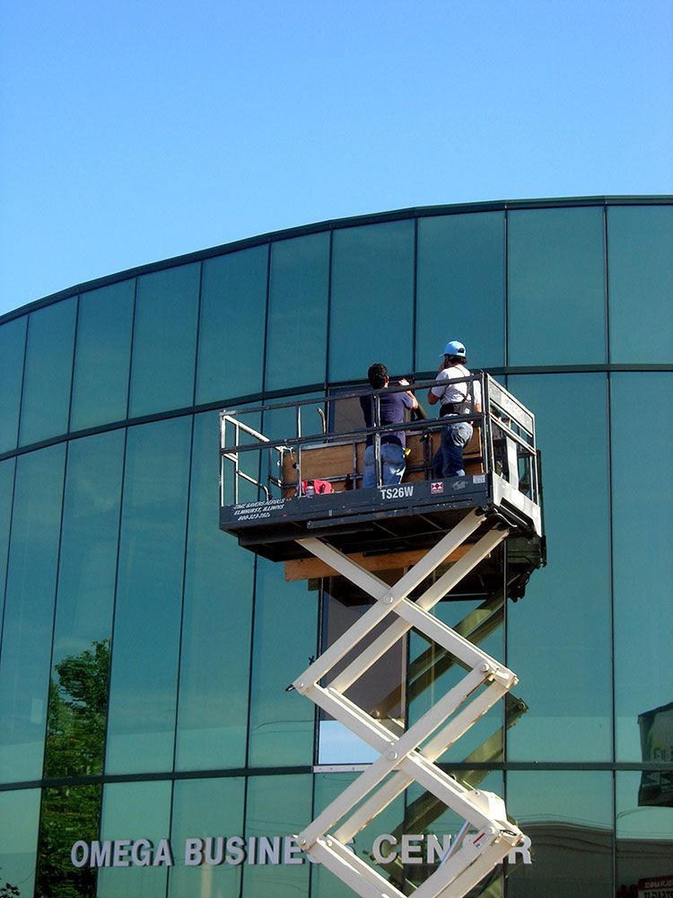 A scissor lift is in front of a building that says omega business center