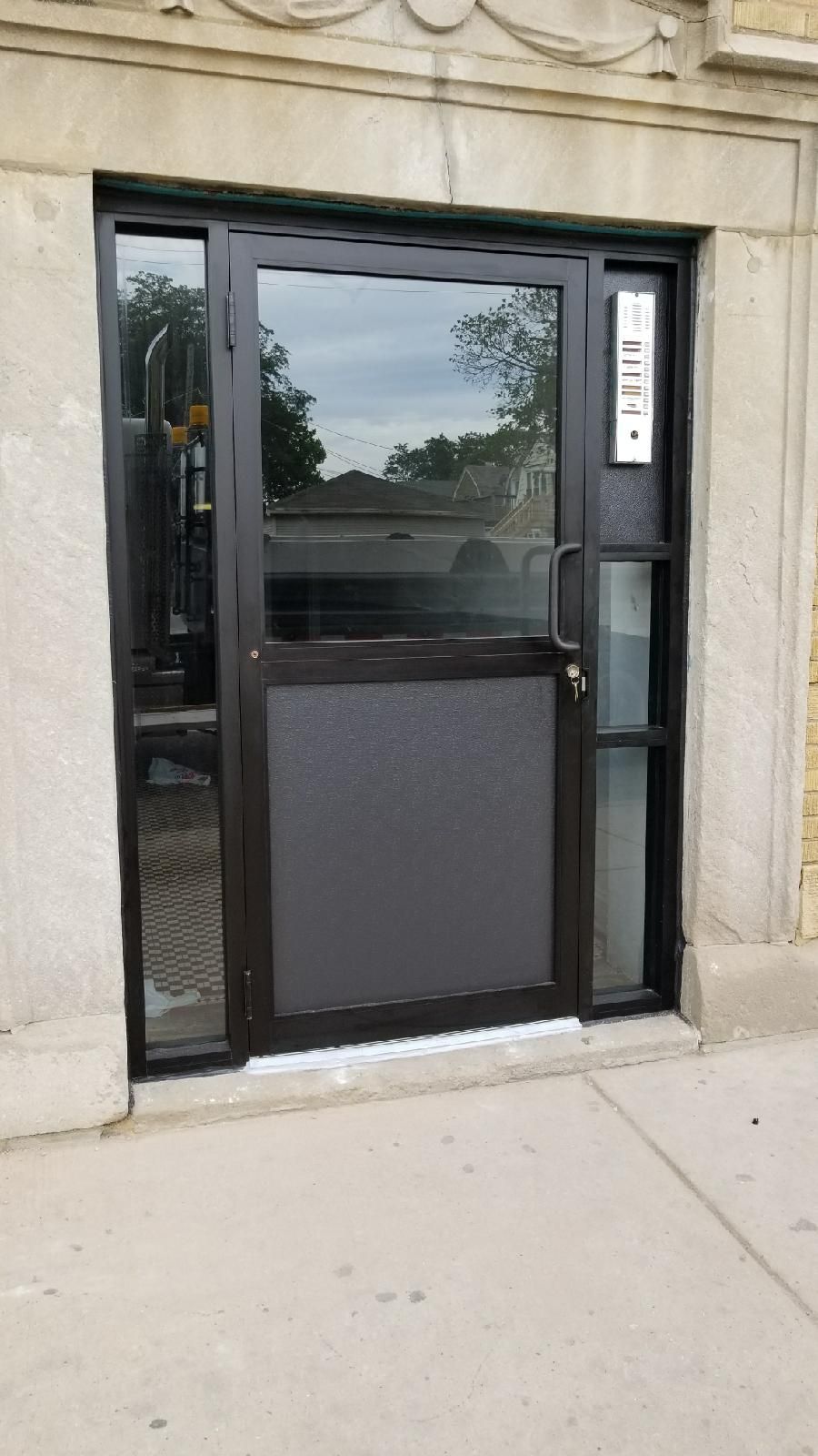 A black door is sitting on the sidewalk in front of a building.