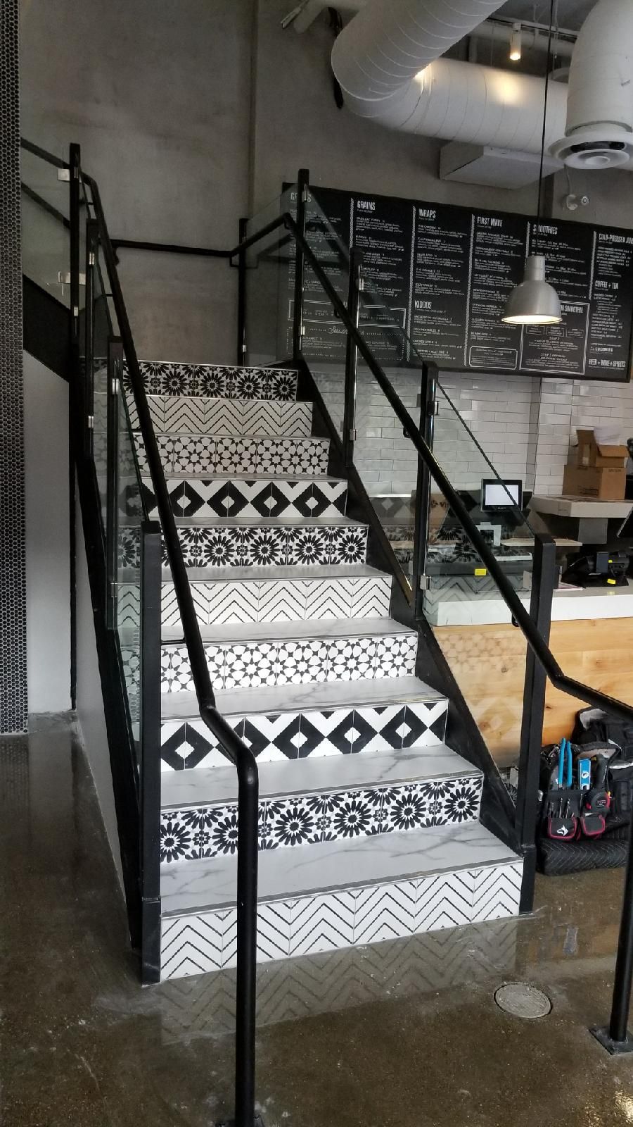 A black and white staircase with a glass railing in a restaurant.