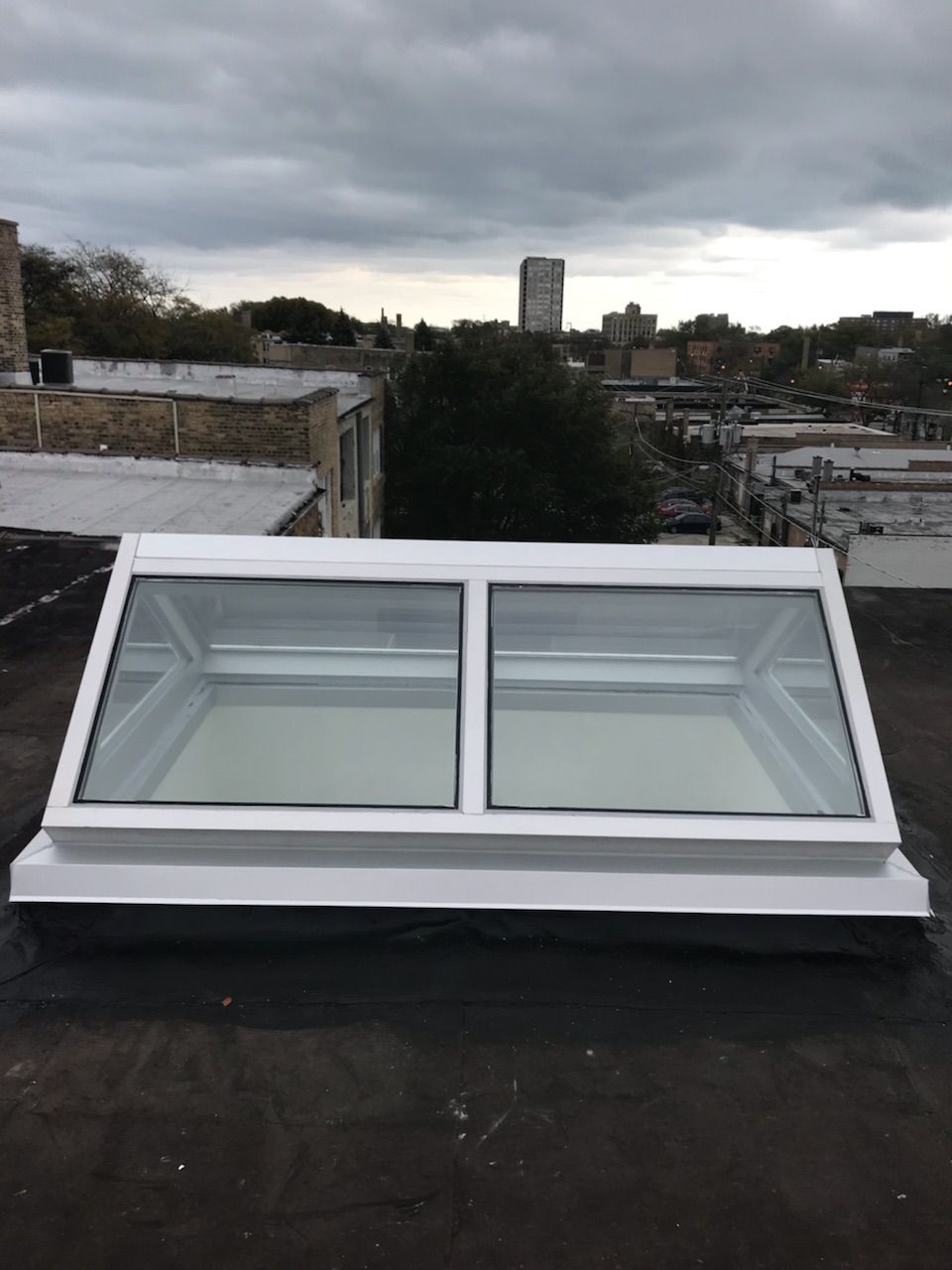 A skylight on the roof of a building with a city in the background