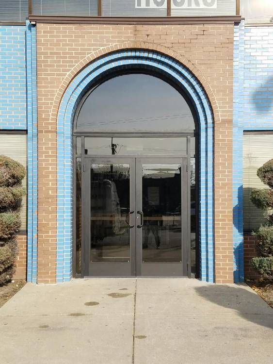 A brick building with a glass door and a blue trim