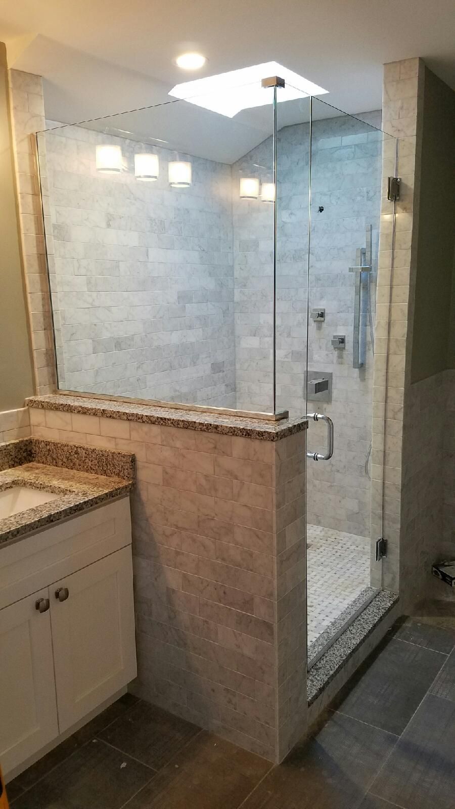 A bathroom with a walk in shower and a sink.