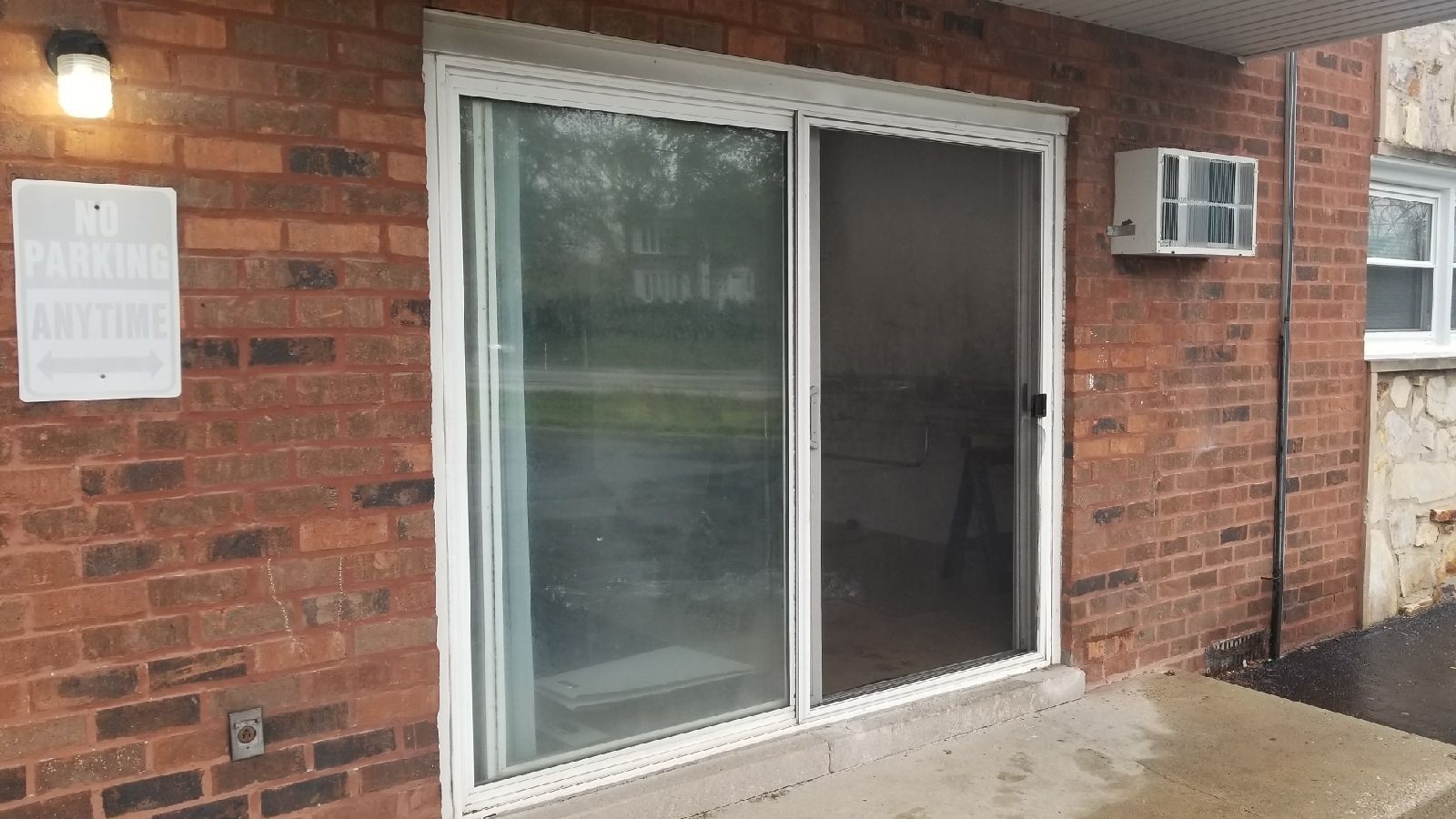 A brick building with a sliding glass door and air conditioner.