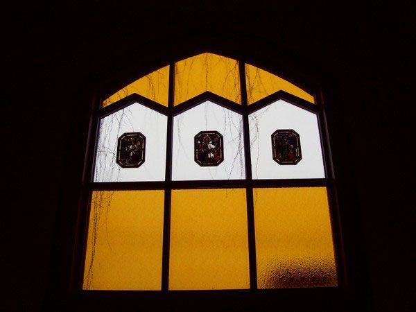 A yellow and white stained glass window with three holes in it