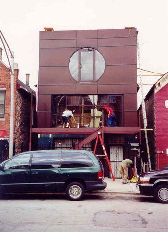 A green van is parked in front of a building