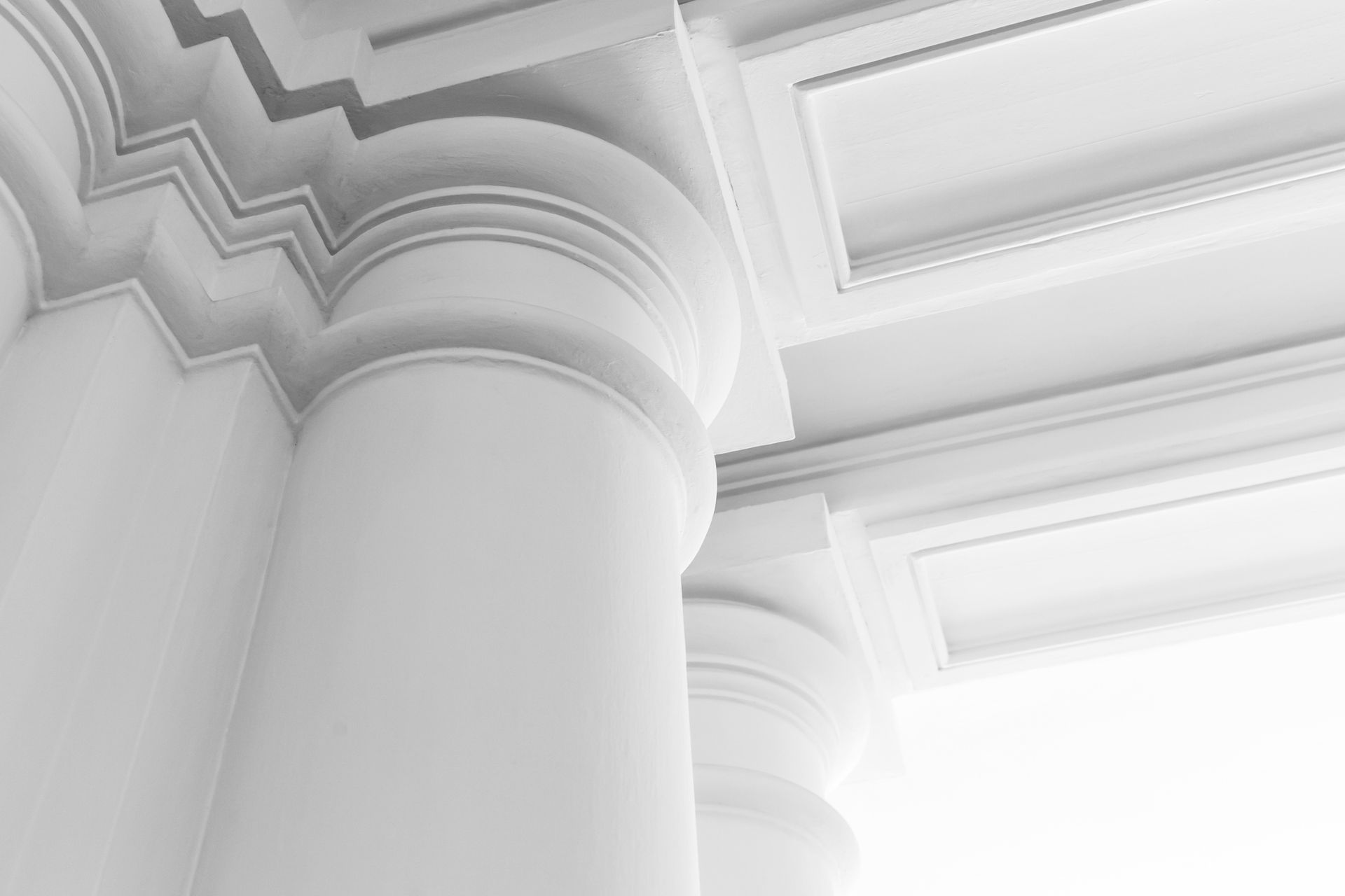 White classical columns and ceiling with ornate details, viewed from a low angle.