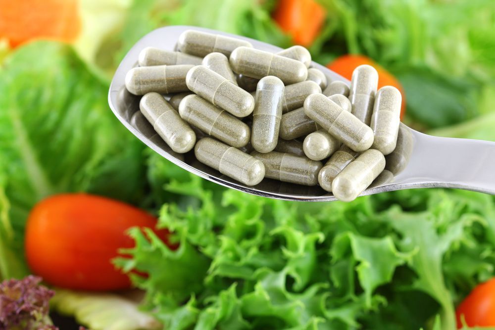 Spoonful of Capsules Over a Bed of Lettuce and Tomatoes — Sugarland Chiropractic Centre in Avoca, QLD