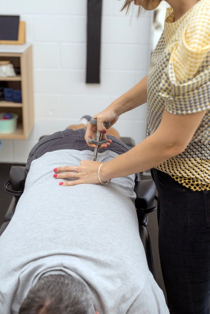 A Woman is Giving a Man a Massage on His Back — Sugarland Chiropractic Centre in Avoca, QLD