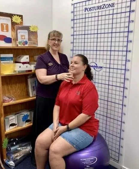 A Woman is Examining a Man 's Neck While He Sits on a Table — Sugarland Chiropractic Centre in Avoca, QLD