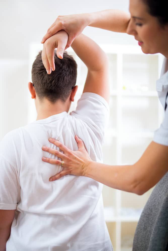 A Woman is Giving a Man a Massage on His Back — Sugarland Chiropractic Centre in Avoca, QLD