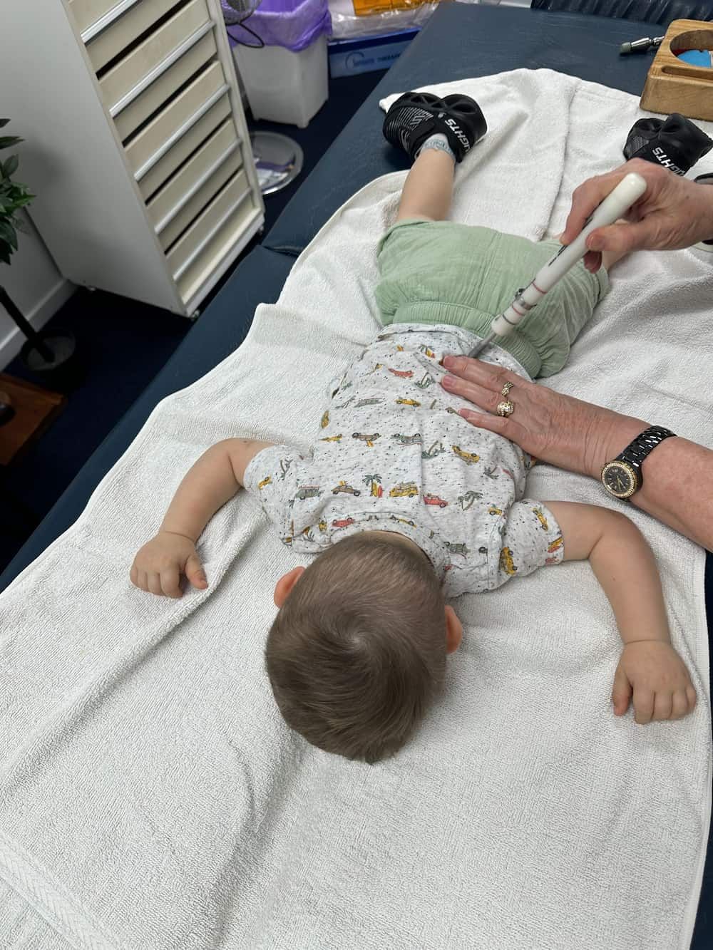 A Baby is Laying on His Back on a Table While a Doctor Examines His Back — Sugarland Chiropractic Centre in Avoca, QLD
