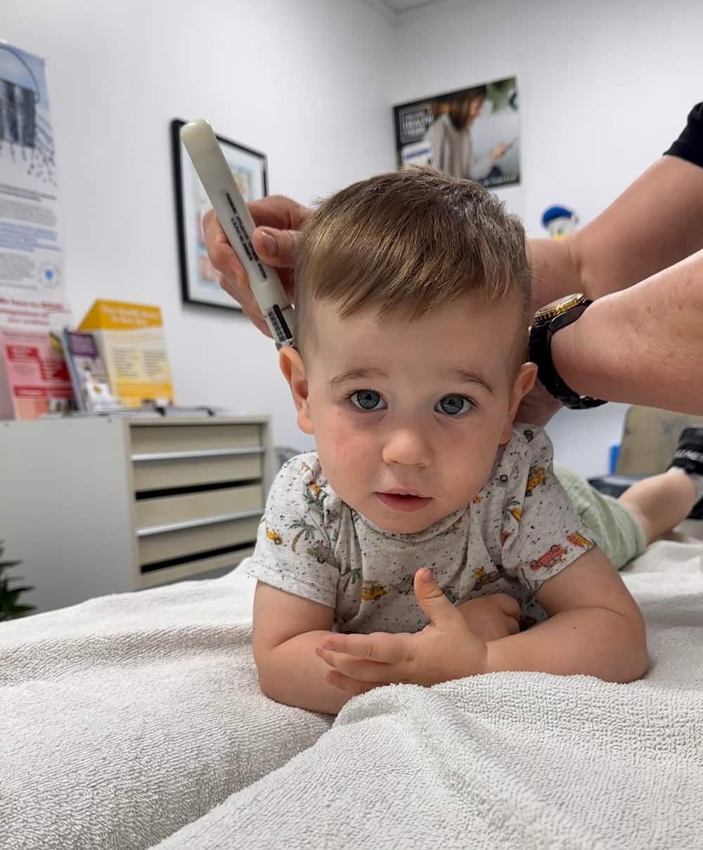 A Baby is Laying on a Bed While His Back is Being Checked — Sugarland Chiropractic Centre in Avoca, QLD