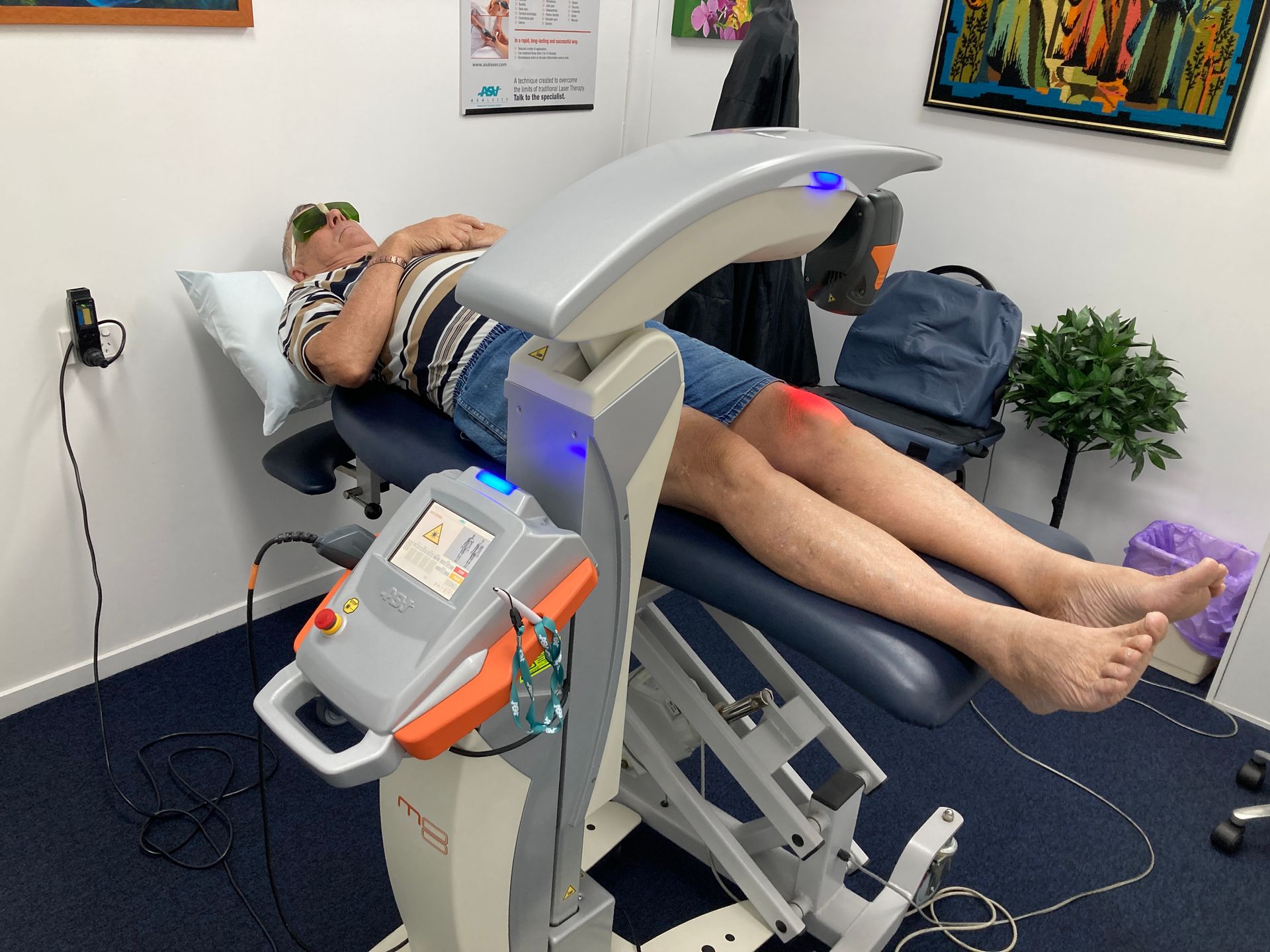 A Woman is Helping an Older Man Lift a Green Dumbbell — Sugarland Chiropractic Centre in Avoca, QLD