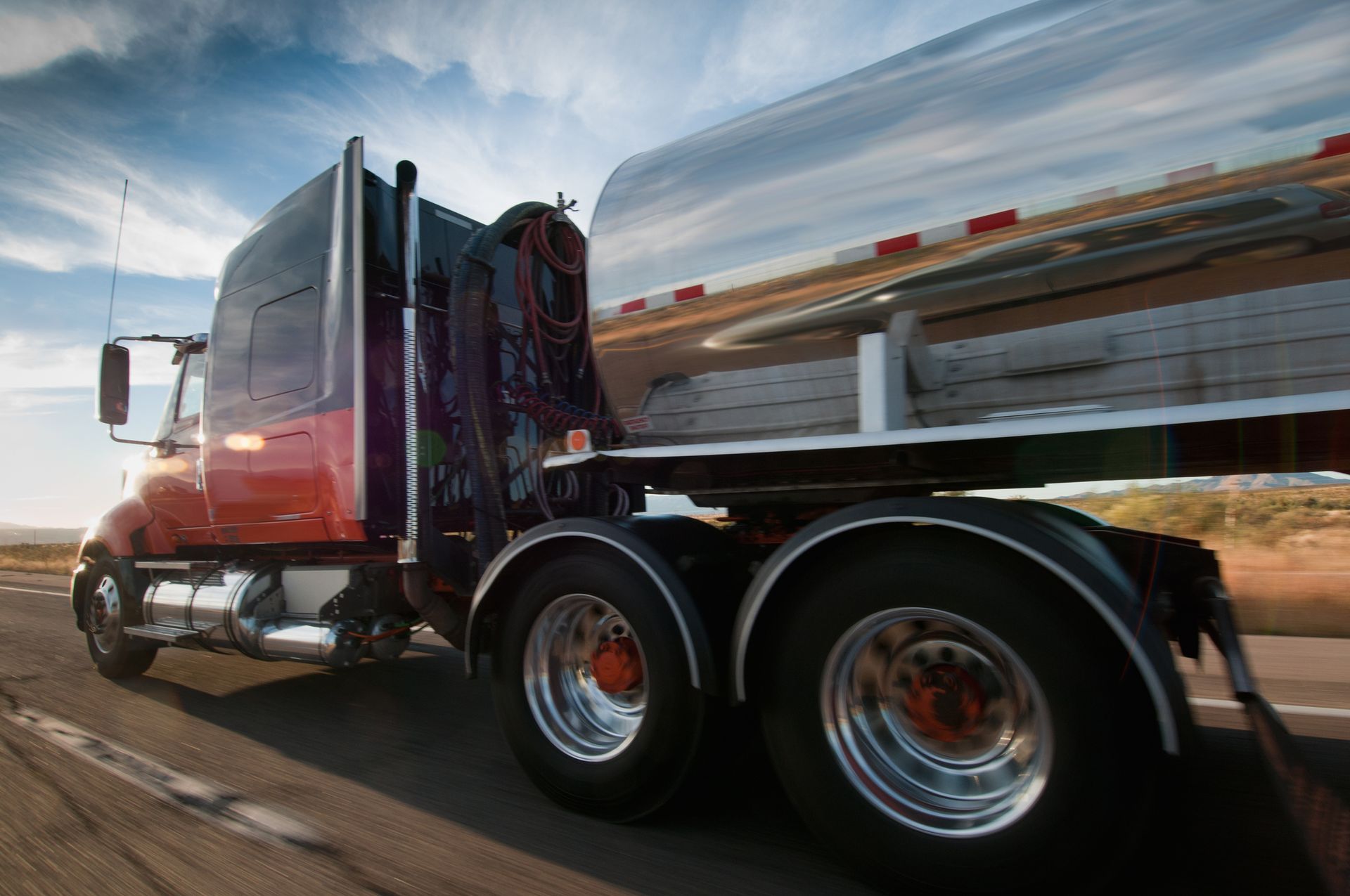 A tanker truck is driving down a highway at sunset.