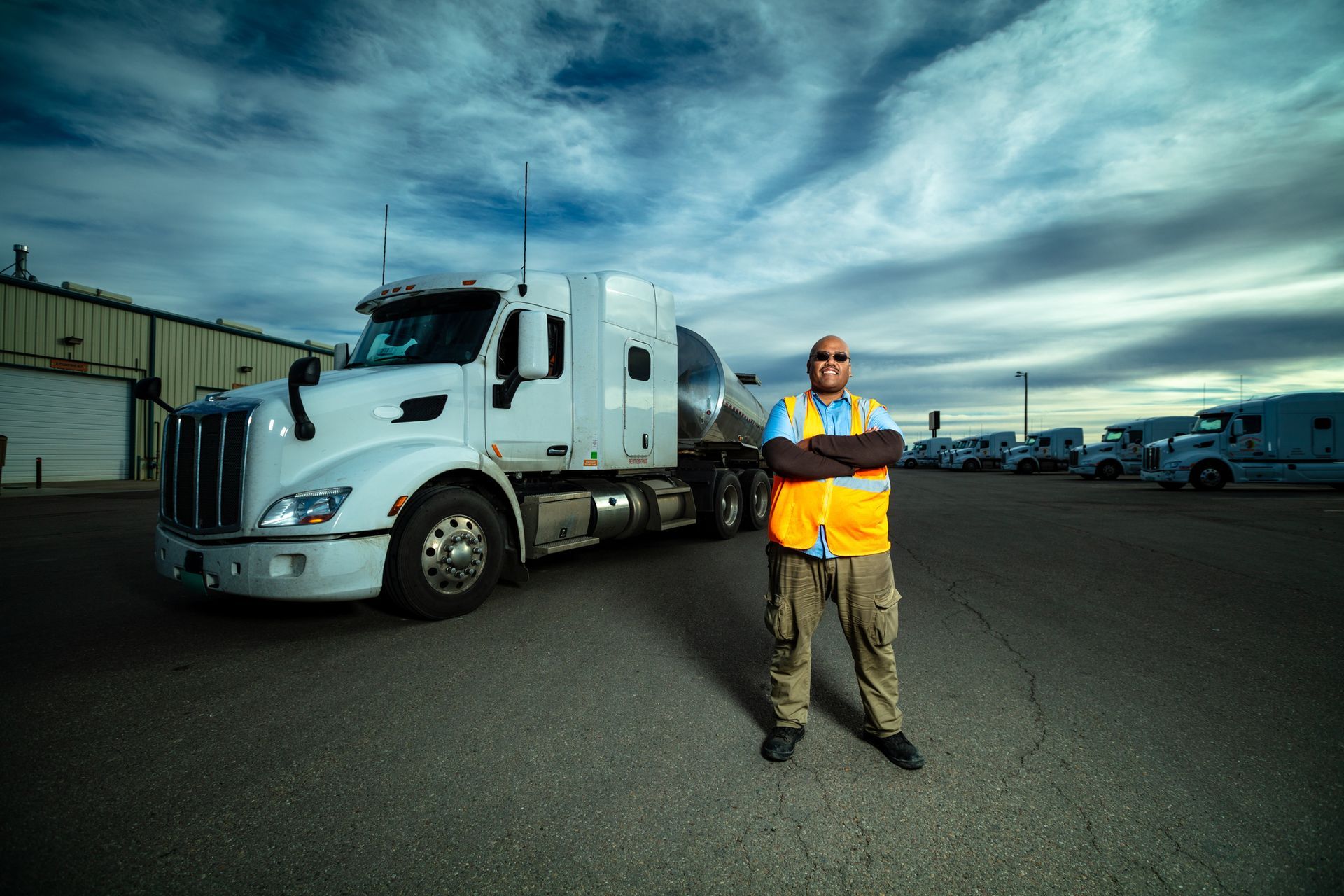 A row of white trucks are driving down a highway.