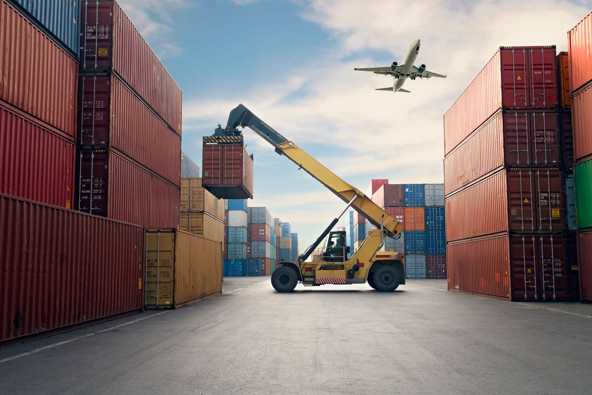 A plane is flying over a warehouse filled with shipping containers.
