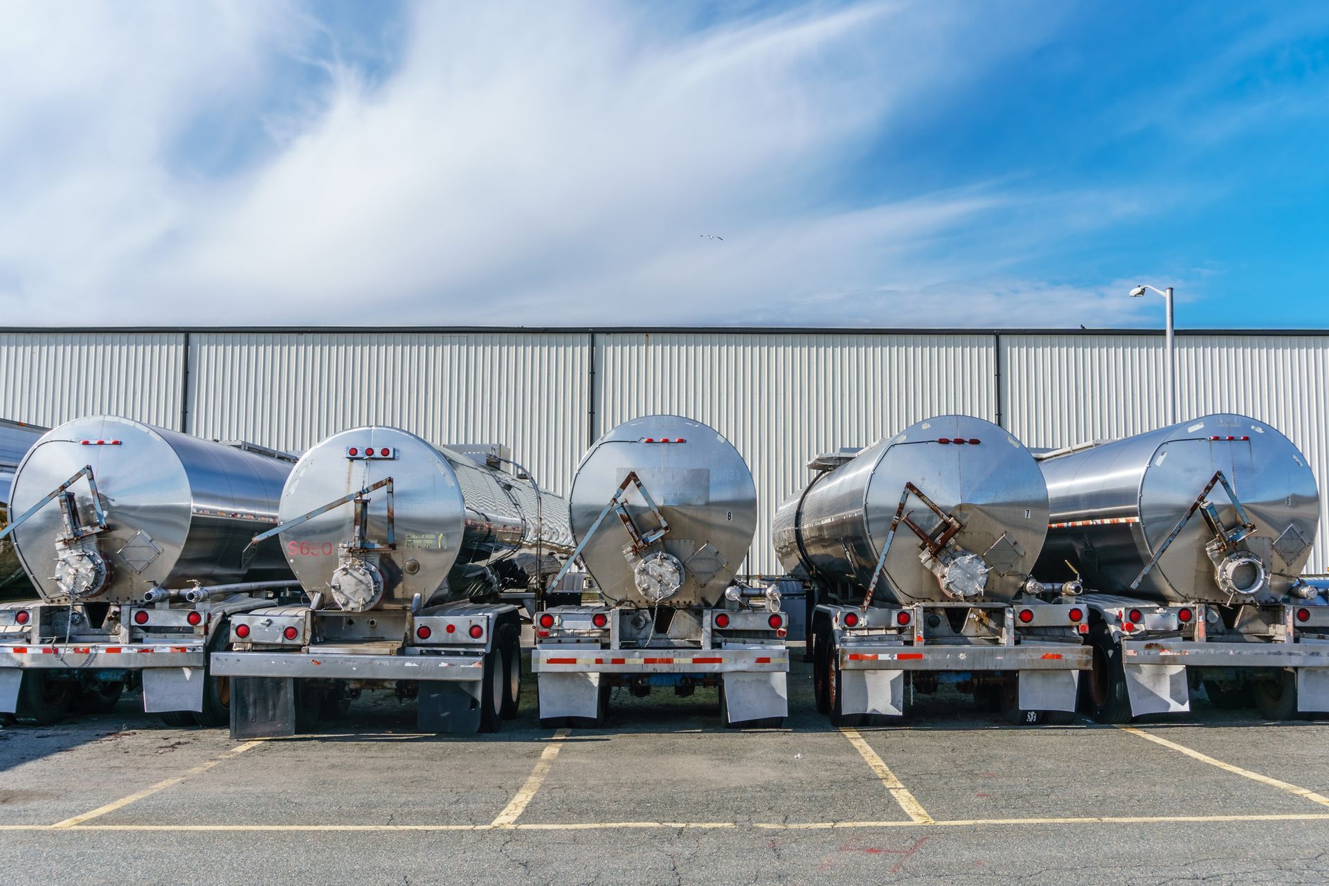 A row of tanker trucks parked in a parking lot in front of a building.