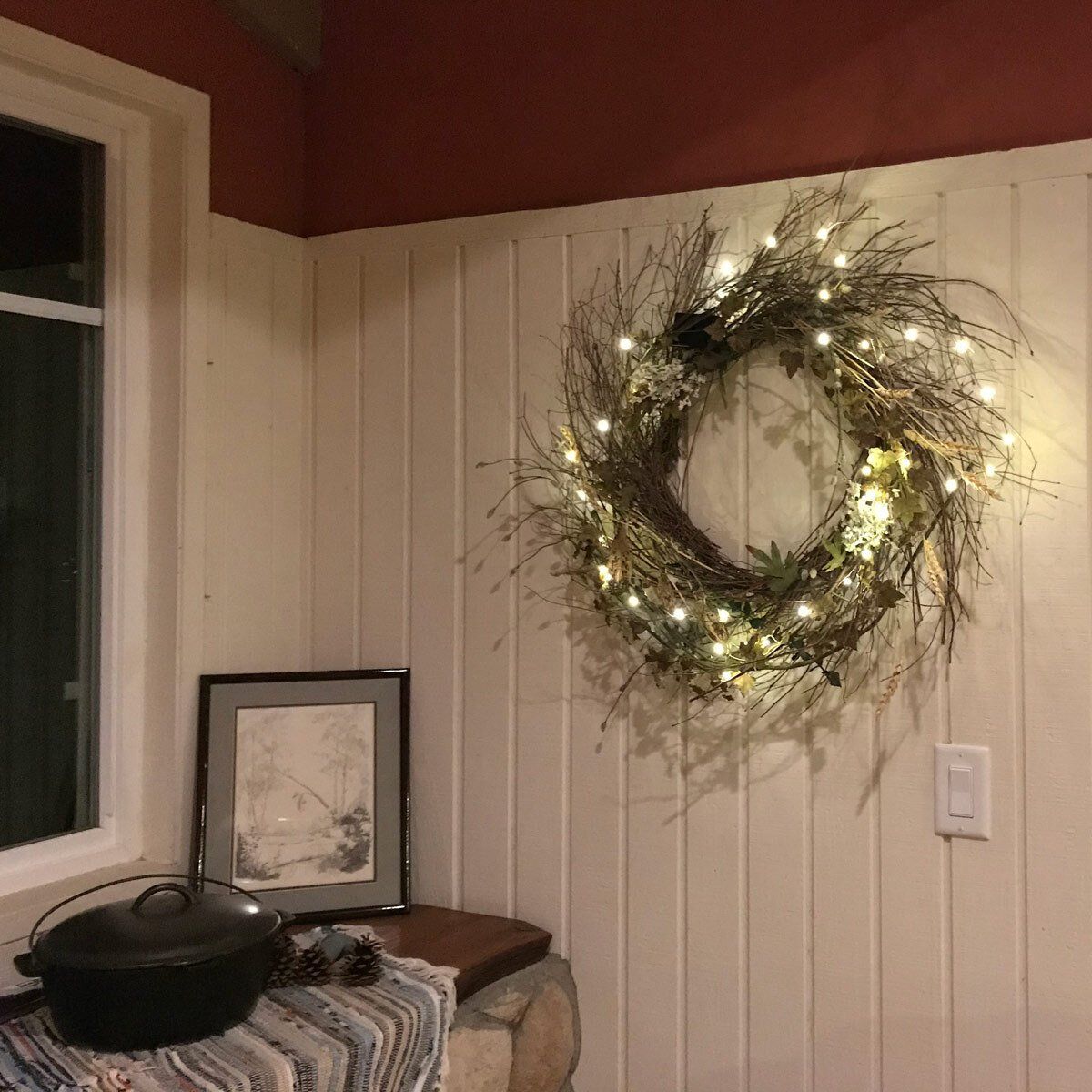 Twinkle lights in Christmas wreath hanging on wall