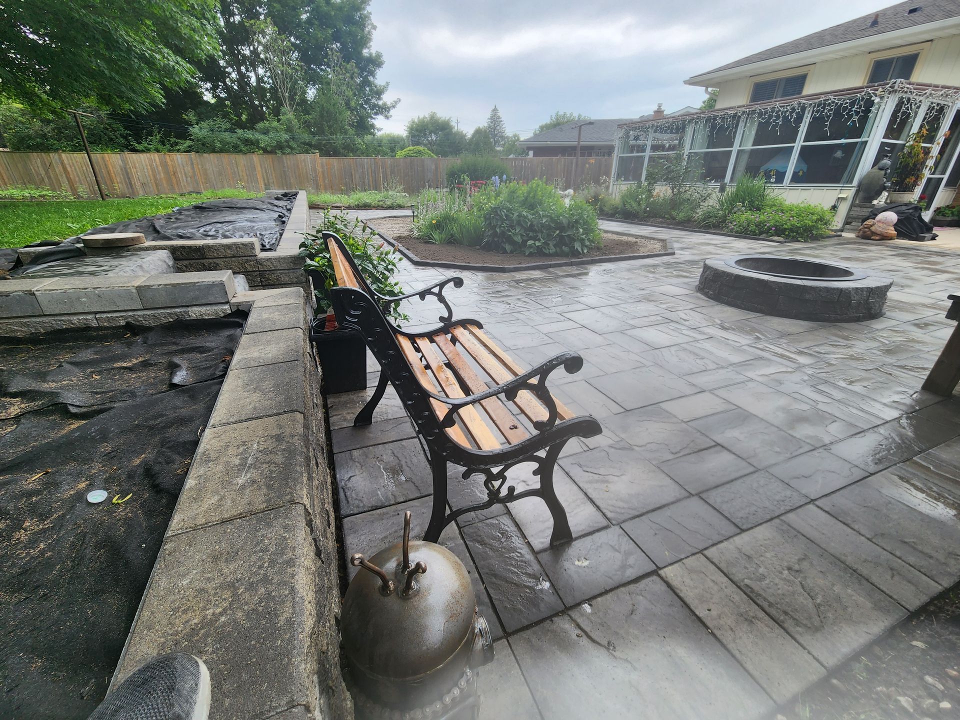 A wooden bench is sitting on a patio next to a fire pit.