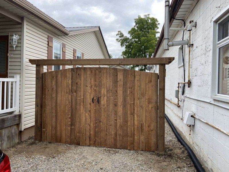 A wooden fence is sitting next to a white house.