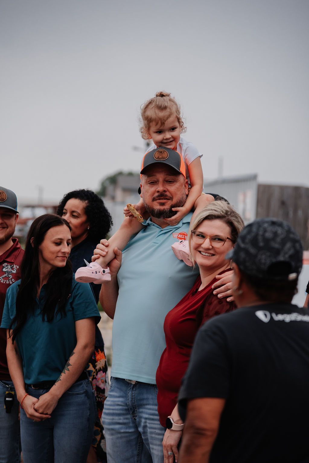 A man is carrying a little girl on his shoulders in a crowd of people. | Chuck's Garage