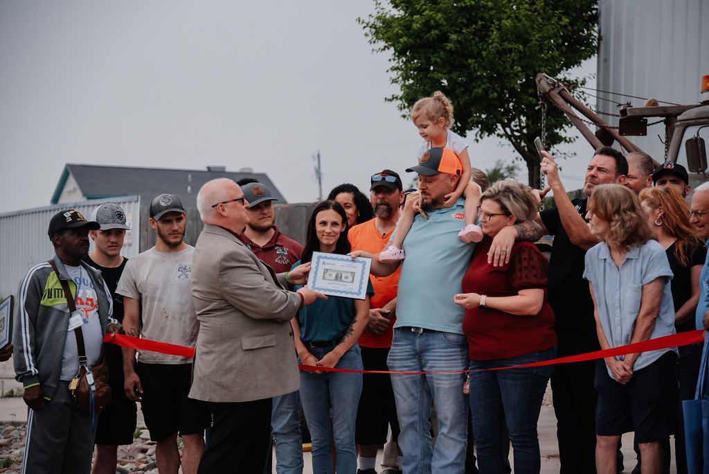 A group of people are standing around a man holding a certificate. | Chuck's Garage