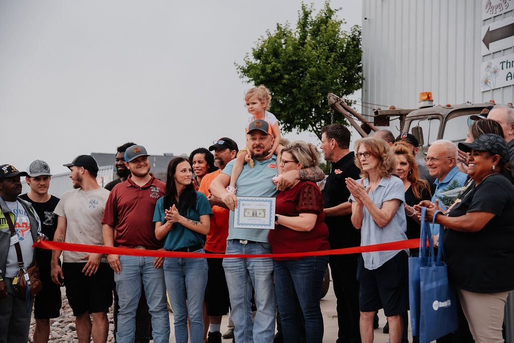 A group of people are standing around a ribbon cutting ceremony. | Chuck's Garage