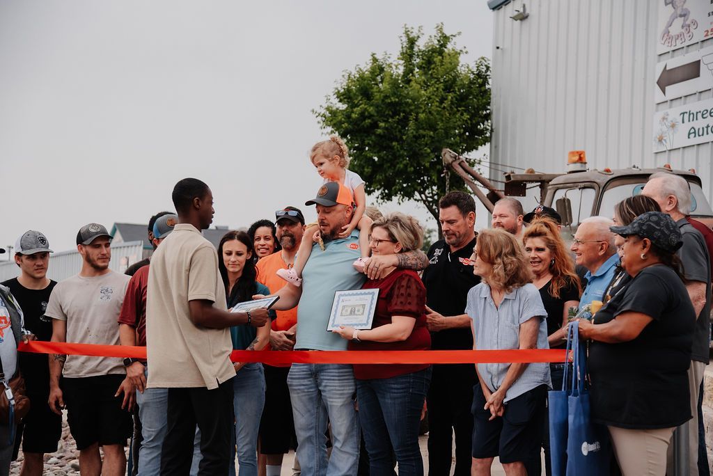 A group of people are standing around a ribbon cutting ceremony. | Chuck's Garage