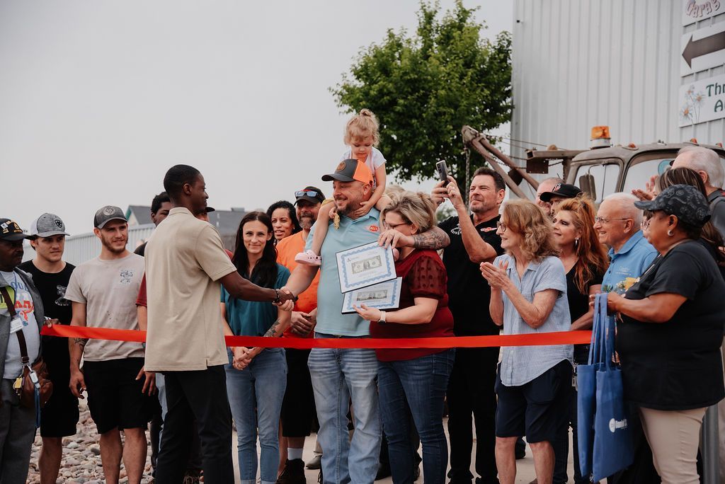 A group of people are standing around a ribbon cutting ceremony. | Chuck's Garage