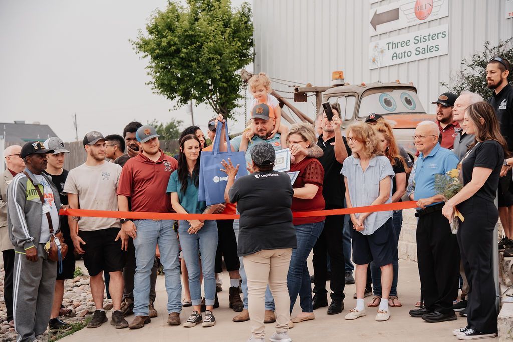 A group of people are standing around a ribbon cutting ceremony. | Chuck's Garage
