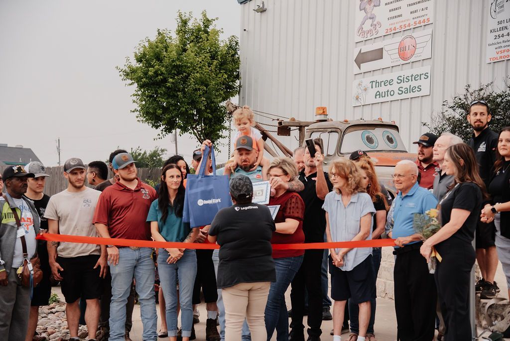 A group of people are standing in front of a building. | Chuck's Garage