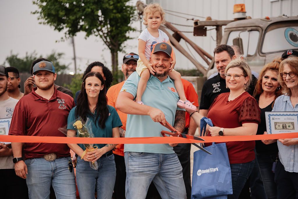 A group of people are standing around a man cutting a red ribbon. | Chuck's Garage