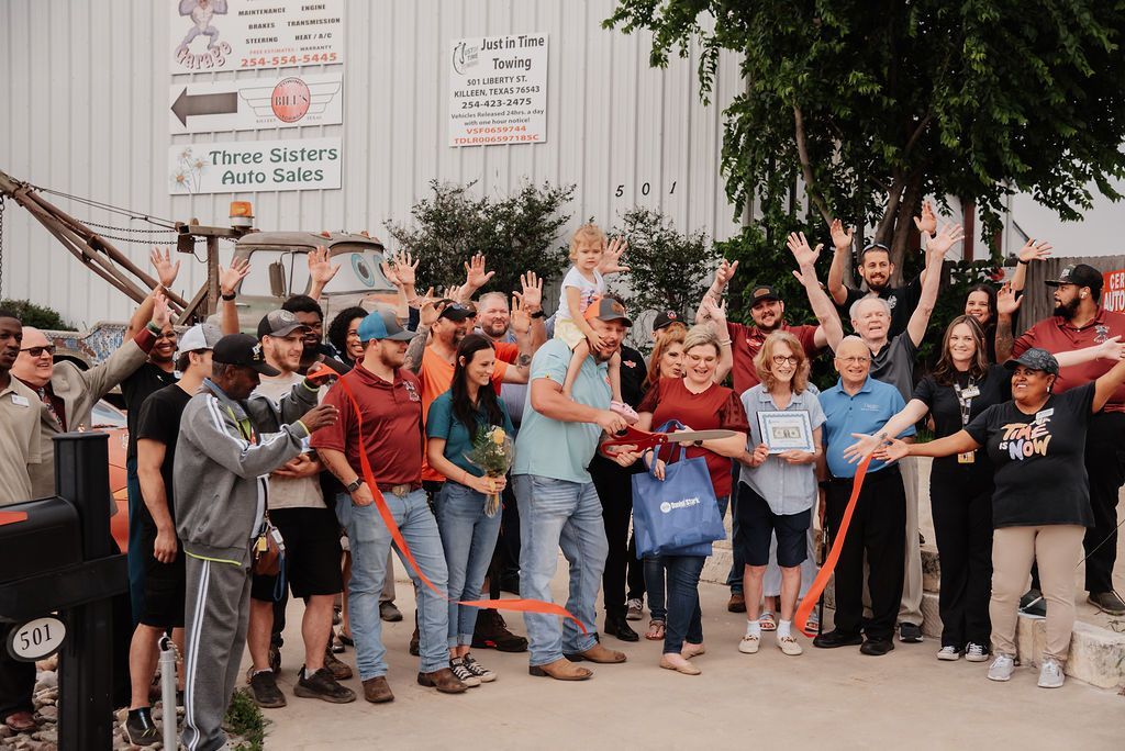 A group of people are standing in front of a building cutting a red ribbon. | Chuck's Garage