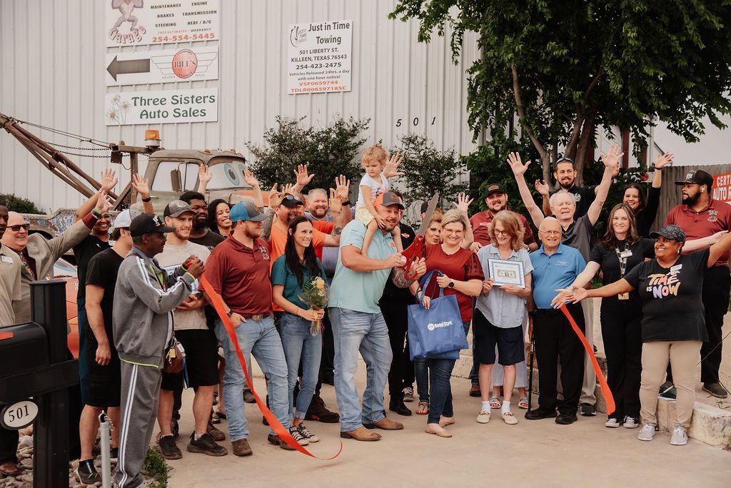 A large group of people are standing in front of a building with their hands in the air. | Chuck's Garage