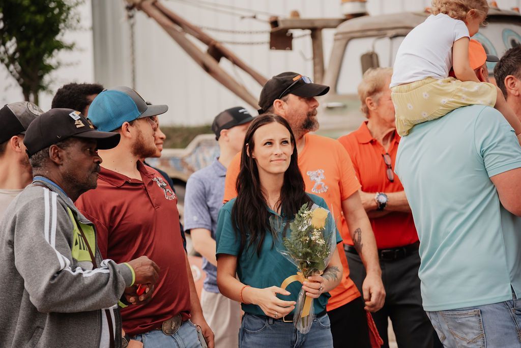 A group of people are standing around a woman holding a bouquet of flowers. | Chuck's Garage