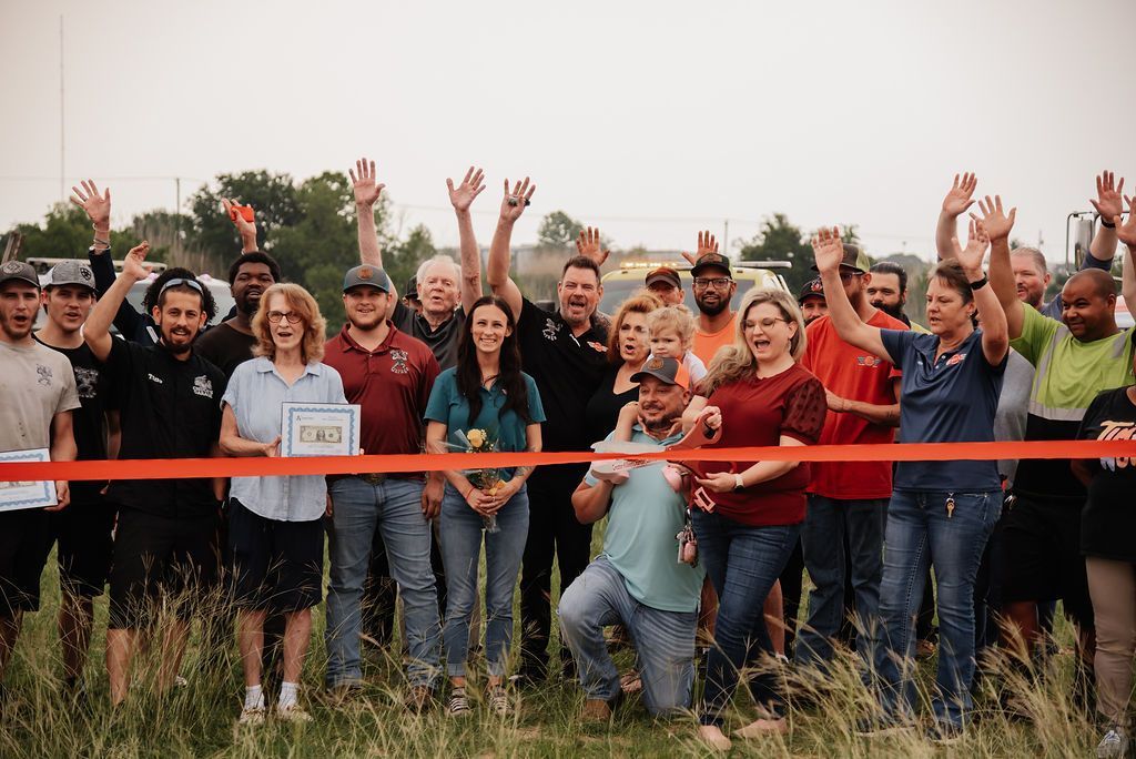 A group of people are standing in a field with their hands in the air. | Chuck's Garage