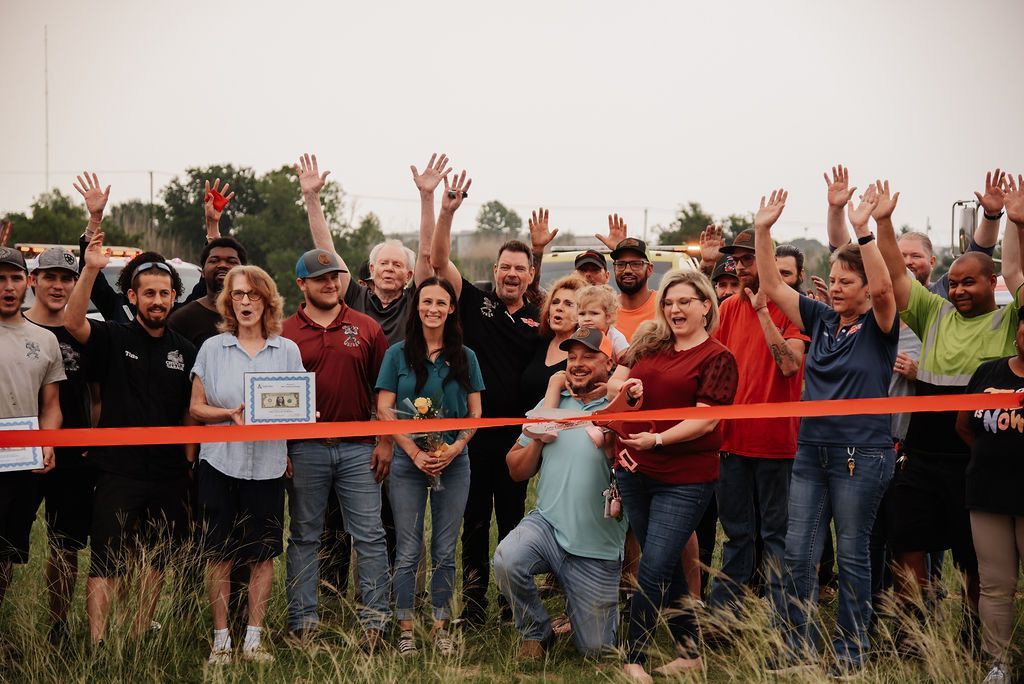 A large group of people are standing in a field with their hands in the air. | Chuck's Garage