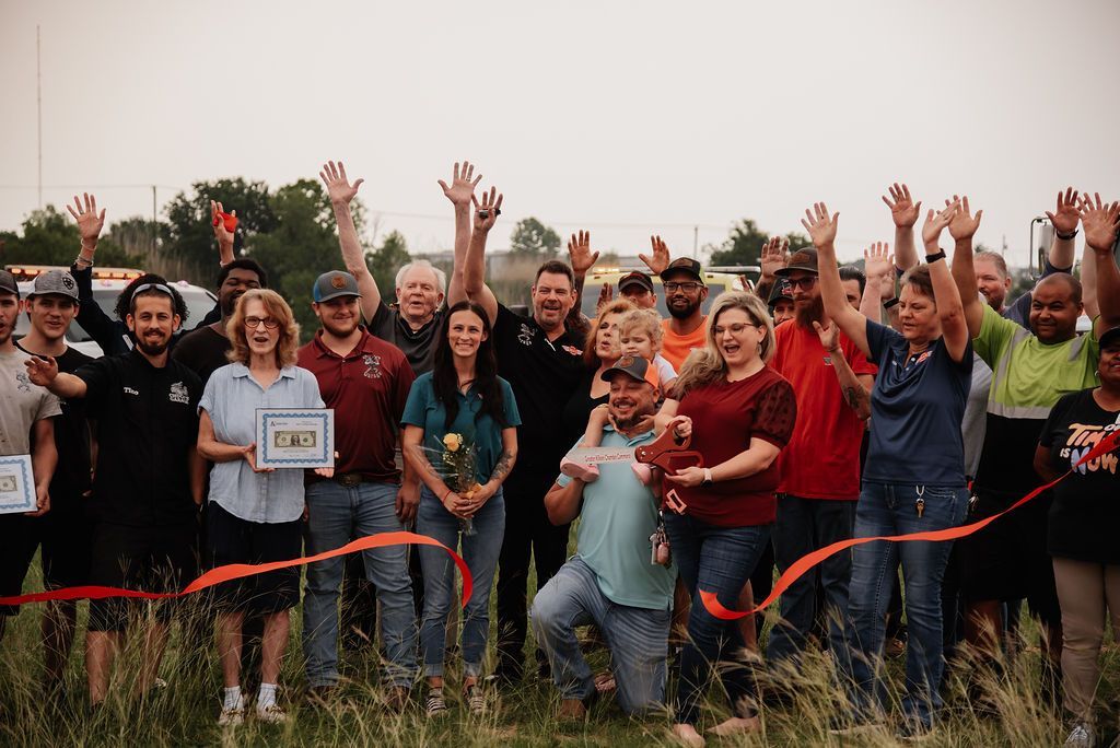 A large group of people are standing in a field with their hands in the air. | Chuck's Garage