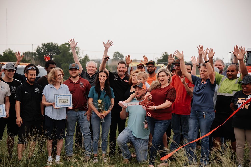 A group of people are standing in a field with their hands in the air. | Chuck's Garage