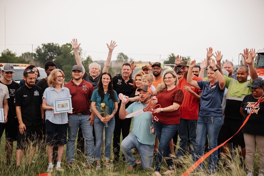 A group of people are standing in a field with their hands in the air. | Chuck's Garage